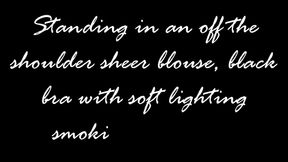 Standing in an off the shoulder blouse and black bra smoking a Virginia Slims menthol 120