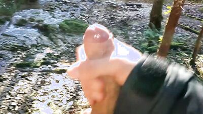 Horny lad is filing his hard pecker while jerking off by the creek