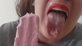 Slowly applying red lipstick while sucking on a strawberry popsicle