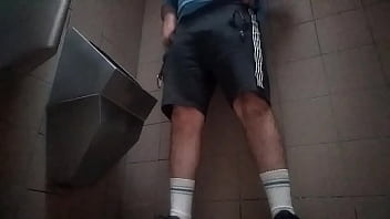 Young guy peeing in a public toilet