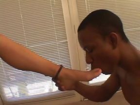 Flat-chested blonde rubs black cock with her feet in living room