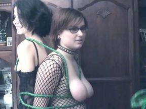 Two busty lesbians in fishnets are tied up together by hot mistress