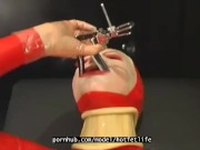 Sexy girl encased in red rubber catsuit loves medical games with mouth spreader and nipple clamps