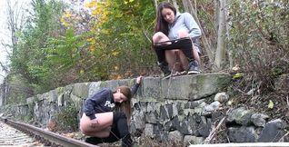 Two friends walk on the train line and search for a place to pee
