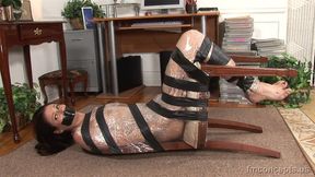 Pinned To A Chair And On The Floor, Secretary Samantha Ryan Is Kept Quiet With Strips Of Tape!