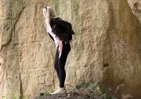 Straight blond haired cutie leans over the rock and pees right away