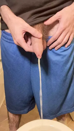 Hairy uncircumcised white guy in gym shorts pissing in the toilet