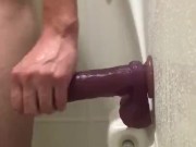 Riding dildo on wall of shower