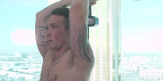 Tattooed man works out with weights and a submissive fella