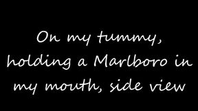 On my tummy showing off more holding a Marlboro menthol 100 in my mouth