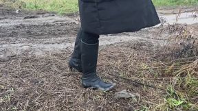 A girl in high-heeled boots walks through mud in bad weather and slides on hills (short version)
