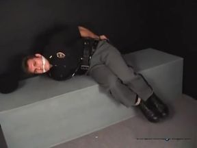 Handsome young policeman cuffed gagged and struggling.