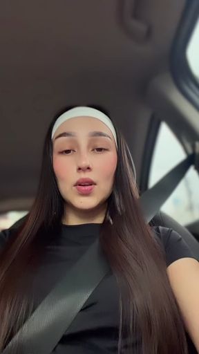 Curvy brunette with long hair and a white headband sits in a car seat