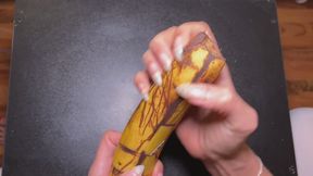 Natural, long, sharp nails destroying banana