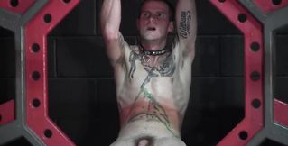 Pouring wax on the body of the tied, tattooed fella