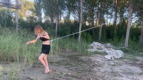 bound girl tries to run barefoot through the slippery mud, but the rope prevents her from escaping