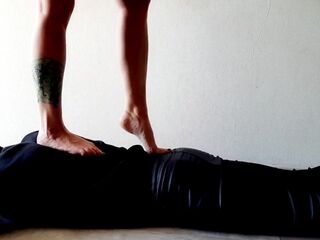 Trampling. Dominatrix Nika walks on the back of her slave with bare feet