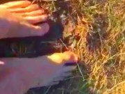 Solo guy rubbing feet in dirt outdoors