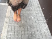 young female hippie is walking barefoot in public street