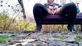 Horny MILF masturbates sitting on a bench through torn pantyhose.