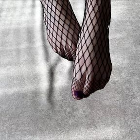 Girl in black fishnet pantyhose caresses her legs