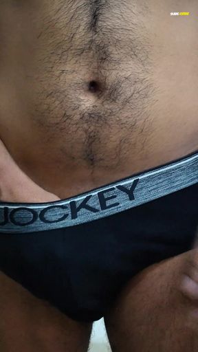 Young man wearing black underwear is dancing cock while holding his groin area.