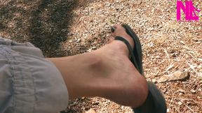 Dangling in black leather flip flops in a garden