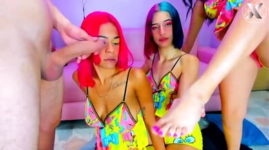 Three women with colorful hair in cartoon dresses take turns on a man's cock