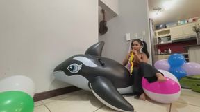 Akina blows up beach balls and pops them