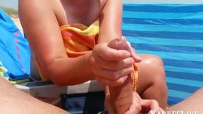 Beach babe gives a naughty handjob in public
