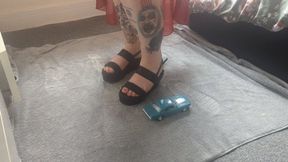 Jayne Vs Ford mustang toy car crush in black wedges with painted toe nails high view