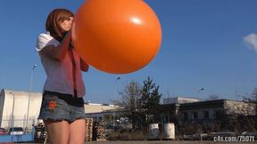 Titi blowing giant orange balloon outdoors (HD quality)