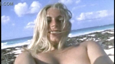 Blonde basks nude on a secluded beach with natural curves on display