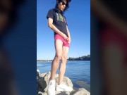 Twink boy with long dark hair pissing pee on the river dressed in glasses cap sneakers boxer tshirt