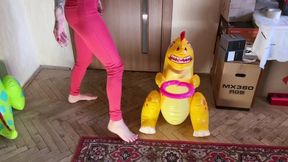a girl barefoot in red tight jeans tramples two inflatable dinosaurs, puts her weight on them, presses foot fetish crash fetish legs jeans