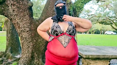 Curvy woman in red lingerie bends over picnic table in park