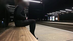 Nighttime tram station display by a crossdresser