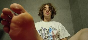 Curly twink shows his legs and jerks off his big dick cumming lots of cum