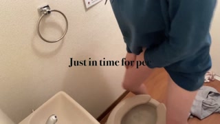 A girl wearing a hoodie rushes into the bathroom on the verge of peeing