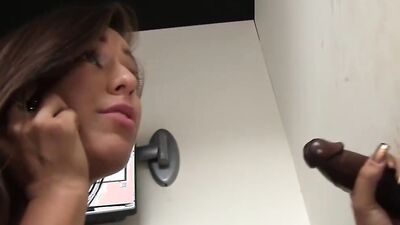Naughty chick goes to a gloryhole to suck big black dicks