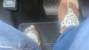 Ebony queen walks in white sandals with a French pedicure and puts her foot on the pedal in a car