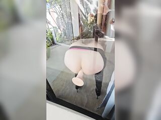 Tiny chienne de Sissy Lola se fait plaisir et s'enfonce un god sur sa baie vitrée en underware.