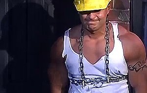 Muscular construction worker is bound up with chains