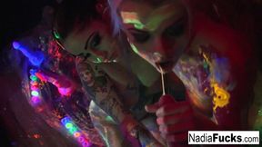 Black-light babes Nadia and Ophelia suck off a colorful cock