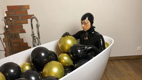 Rubbermissy is enjoying a balloon bath filled with black and gold latex balloons latexsound mask fetish