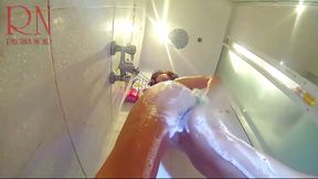 Camera in the shower. A young nude girl in the shower is washed with soap.