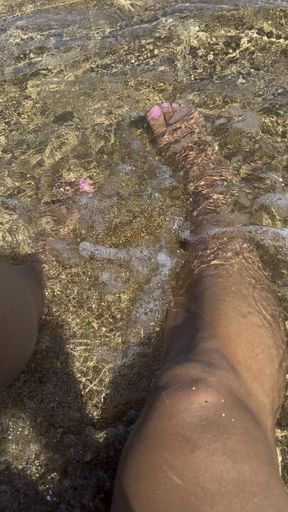 Feet in sand with clear waters