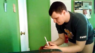 Man prepares an enema in diaper briefs with buttocks exposed in a green room