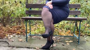 Lustful MILF in a long skirt and stockings masturbates on a park bench