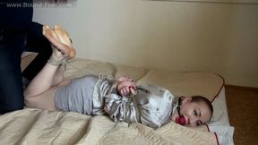 Ballgagged barefoot Amanda in grey shirt and shorts, hogtied with her thumbs tied up, is getting her feet oiled and tickled (HD MP4)